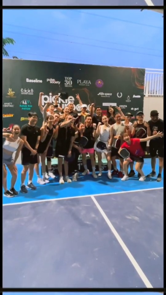 Group of players cheering in front of a Pickle4Purpose backdrop at the Pickle4Purpose Celebrity Match