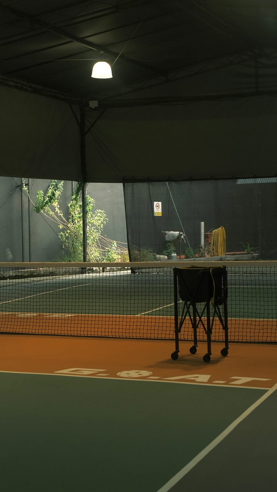 An indoor pickleball court at GOAT Pickle Club in Penang, with the club's G.O.A.T logo painted on the court surface