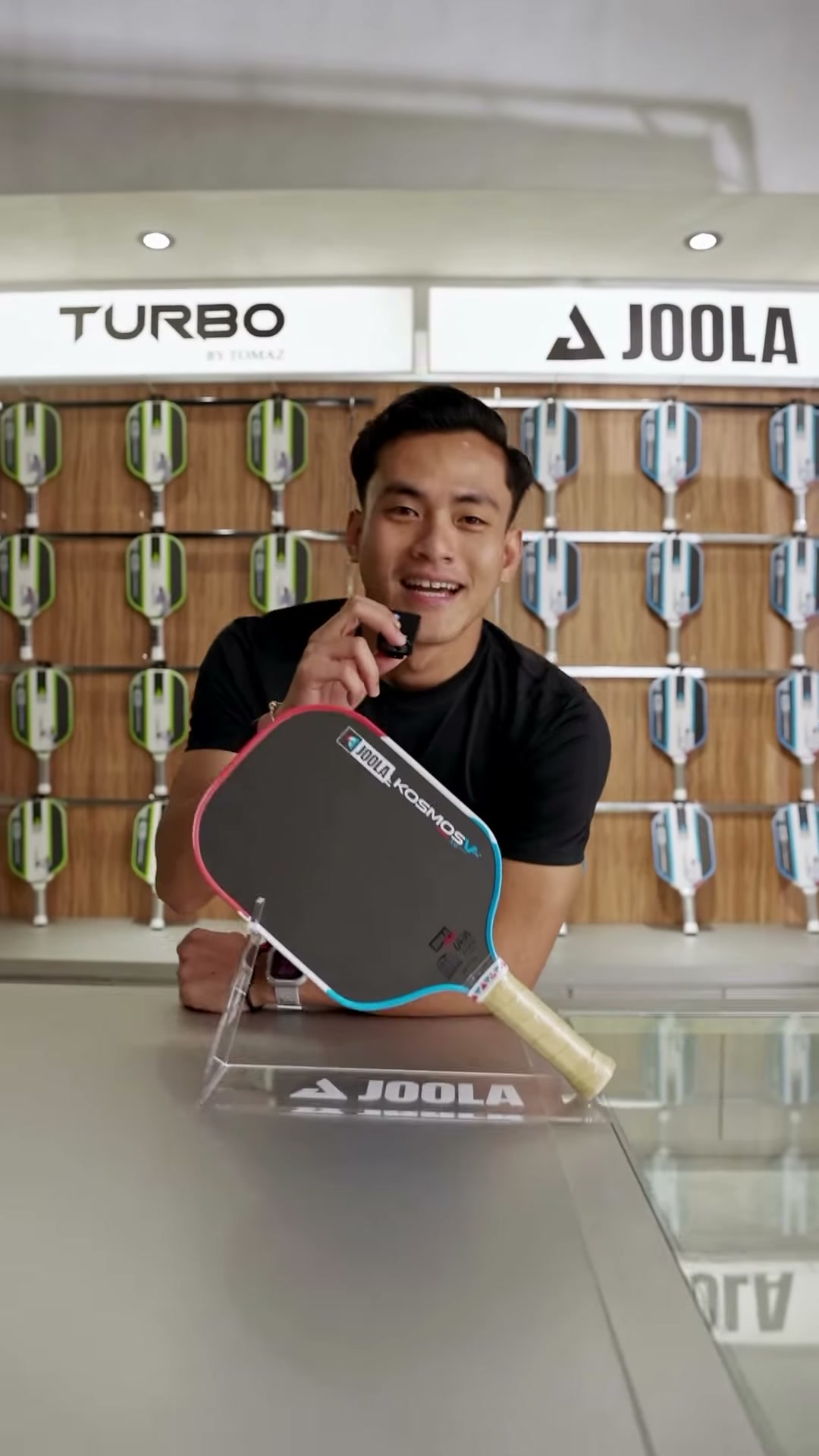 Aiman Hamdan holding a JOOLA Kosmos V+ paddle courtside at Tomaz Pickleball Club, promoting the PPA 125 Tomaz Cup