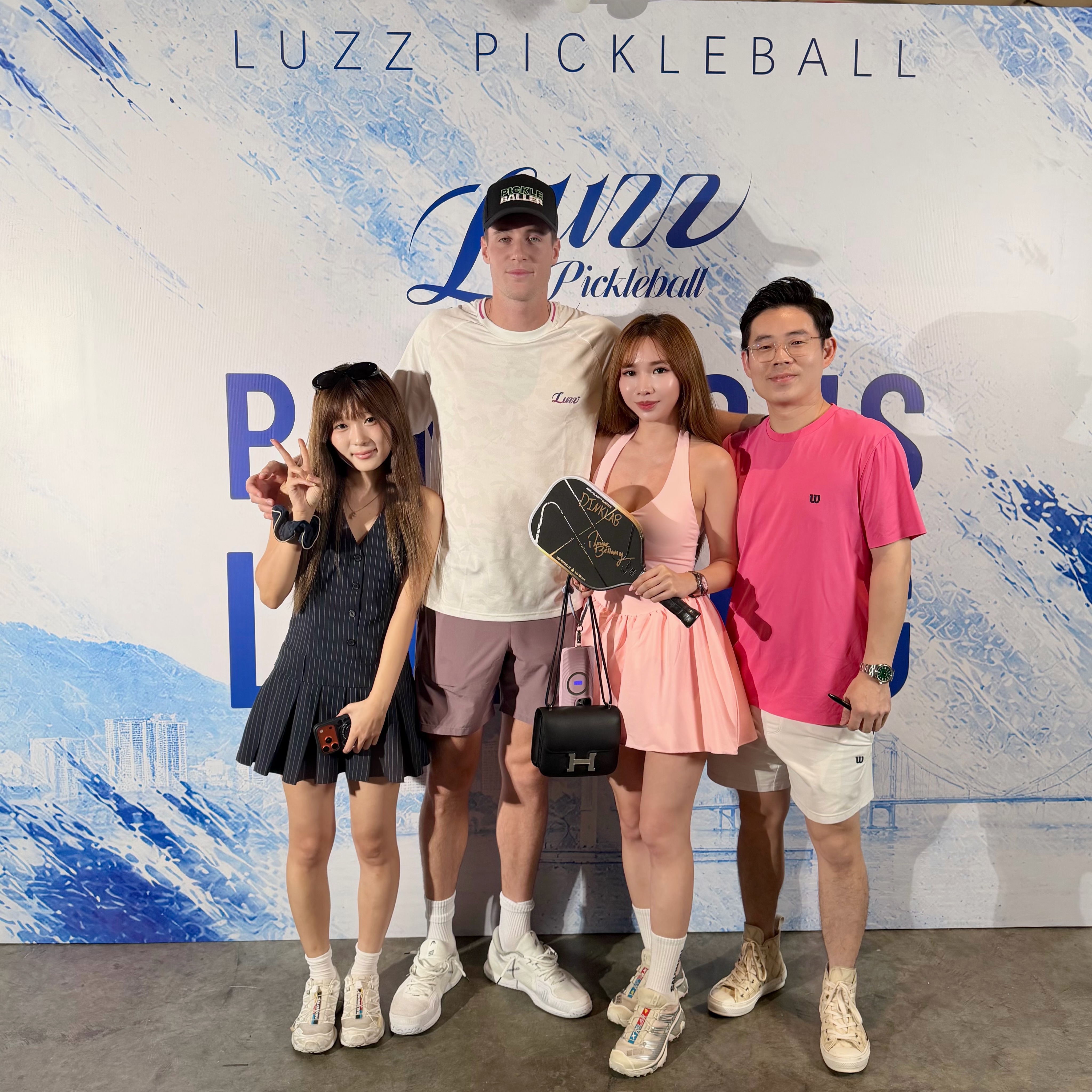 Roscoe Bellamy signs a paddle for fans in front of the Luzz Pickleball backdrop at Pickle By The Sea.