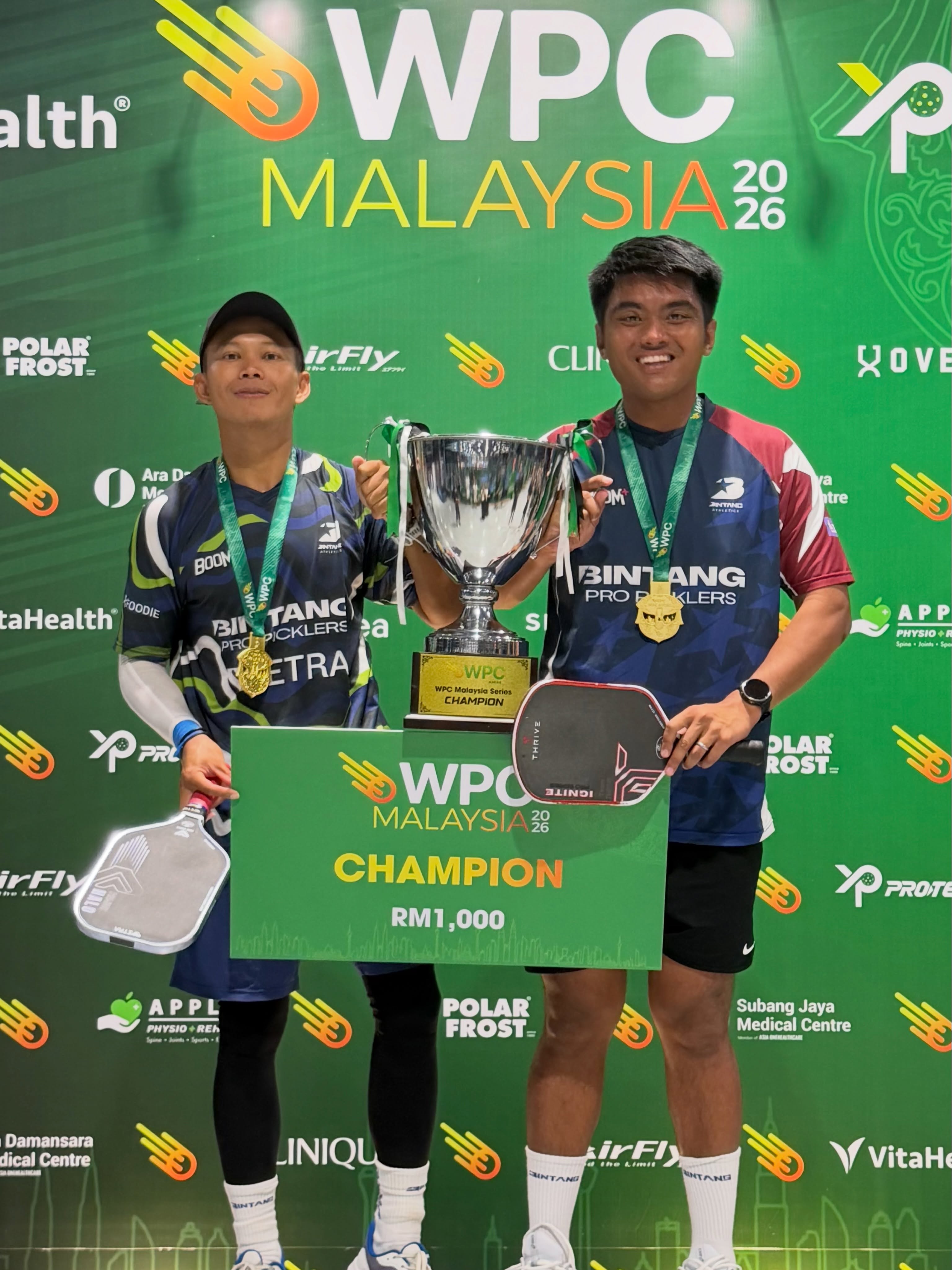 Ashaari Zainal stands with his Double 35+ Open gold-medal partner, holding the champion trophy.