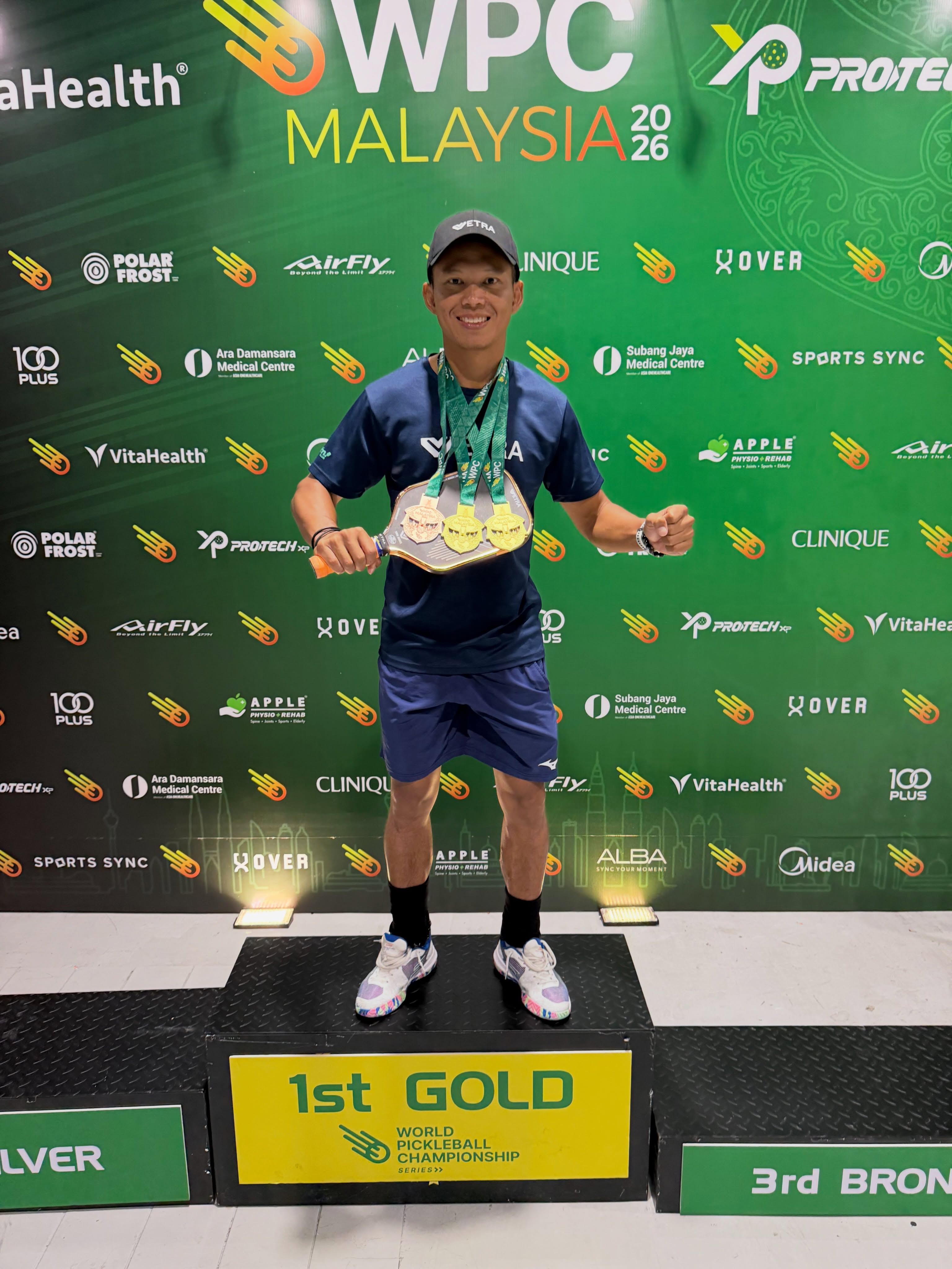Ashaari Zainal stands on the 1st Gold podium at WPC Malaysia 2026 wearing three medals.