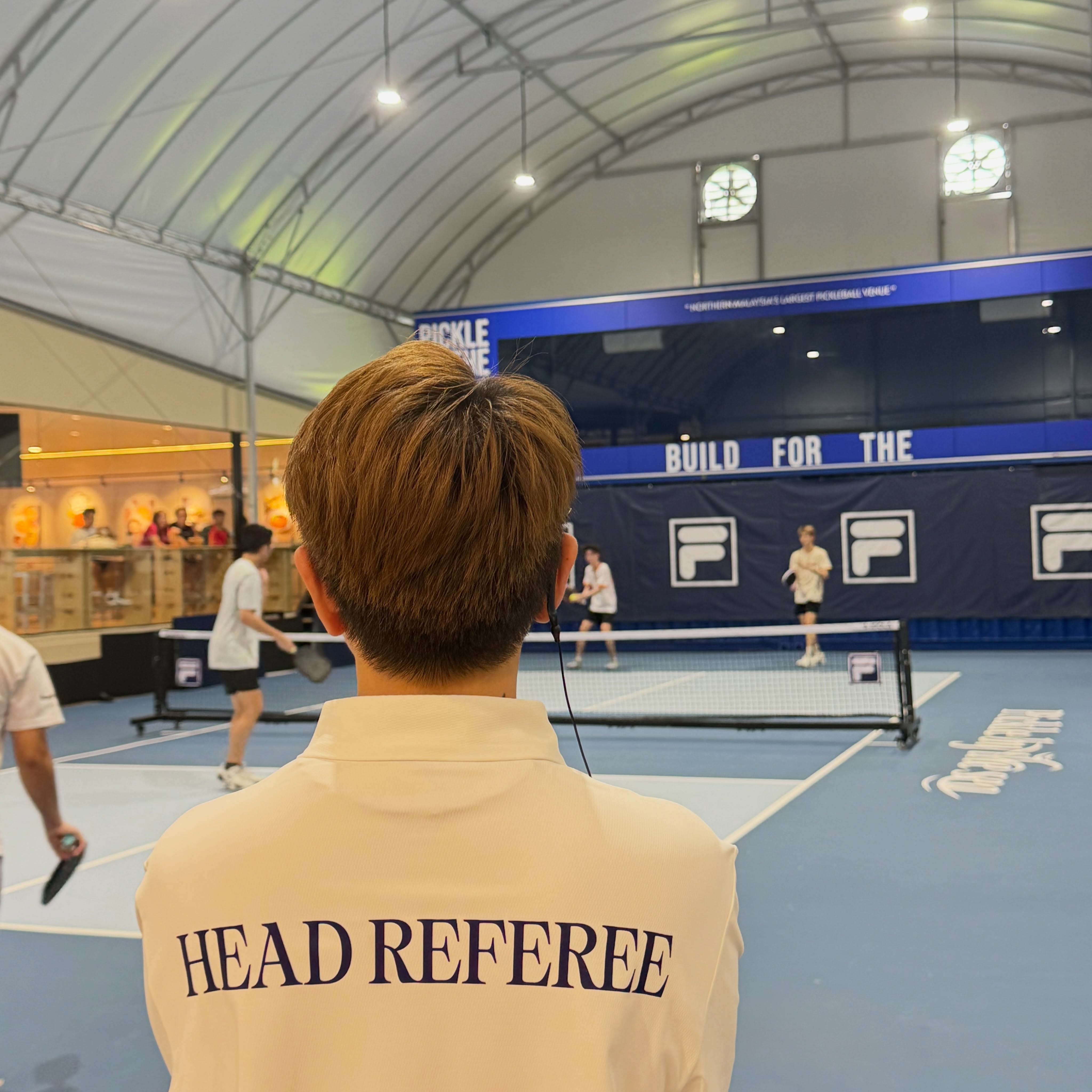 A PxRef official calls a match at FILA Country Club, backed by JOOLA's court branding