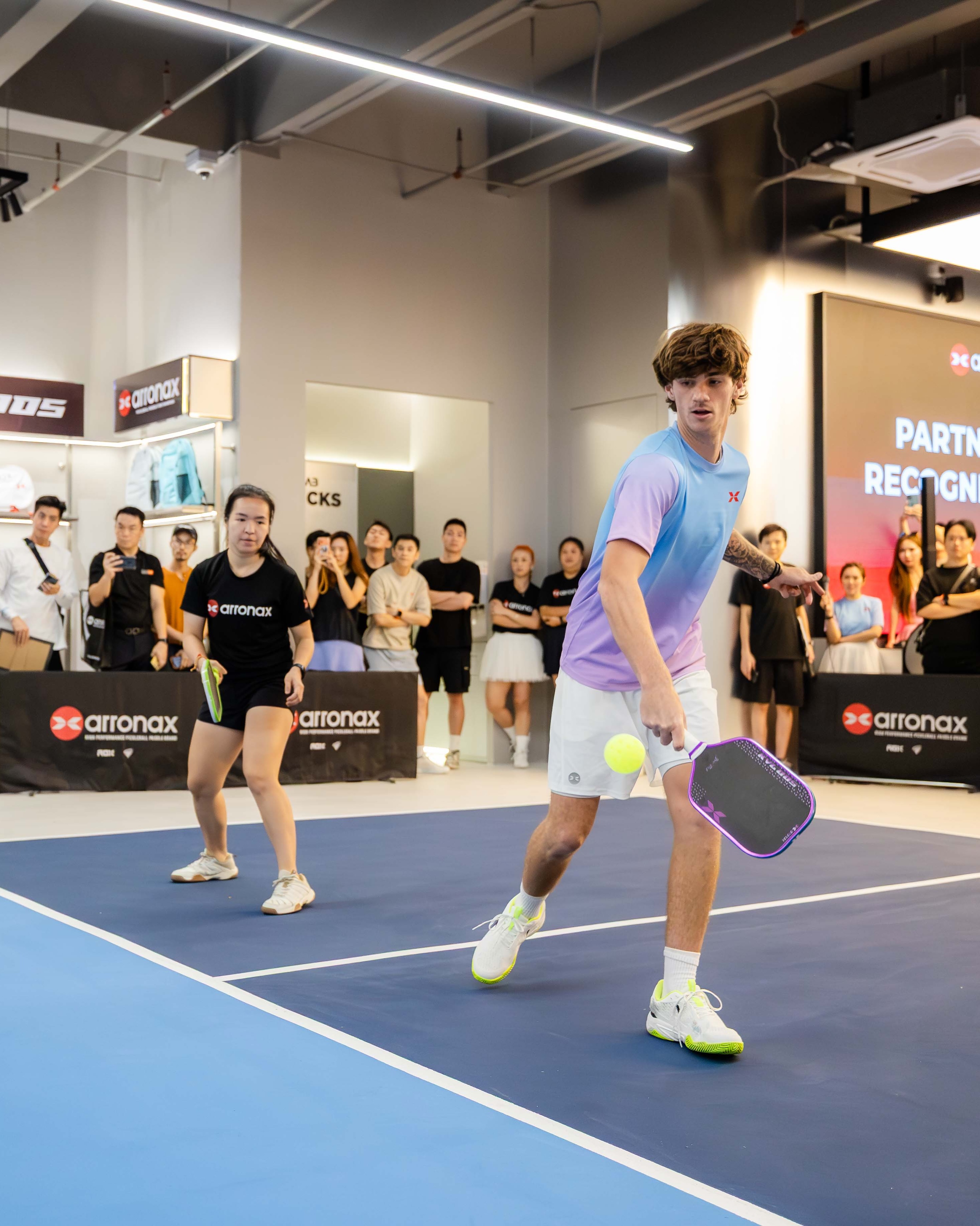 Zane Ford playing on court at an Arronax community event in Kuala Lumpur, with a crowd watching courtside