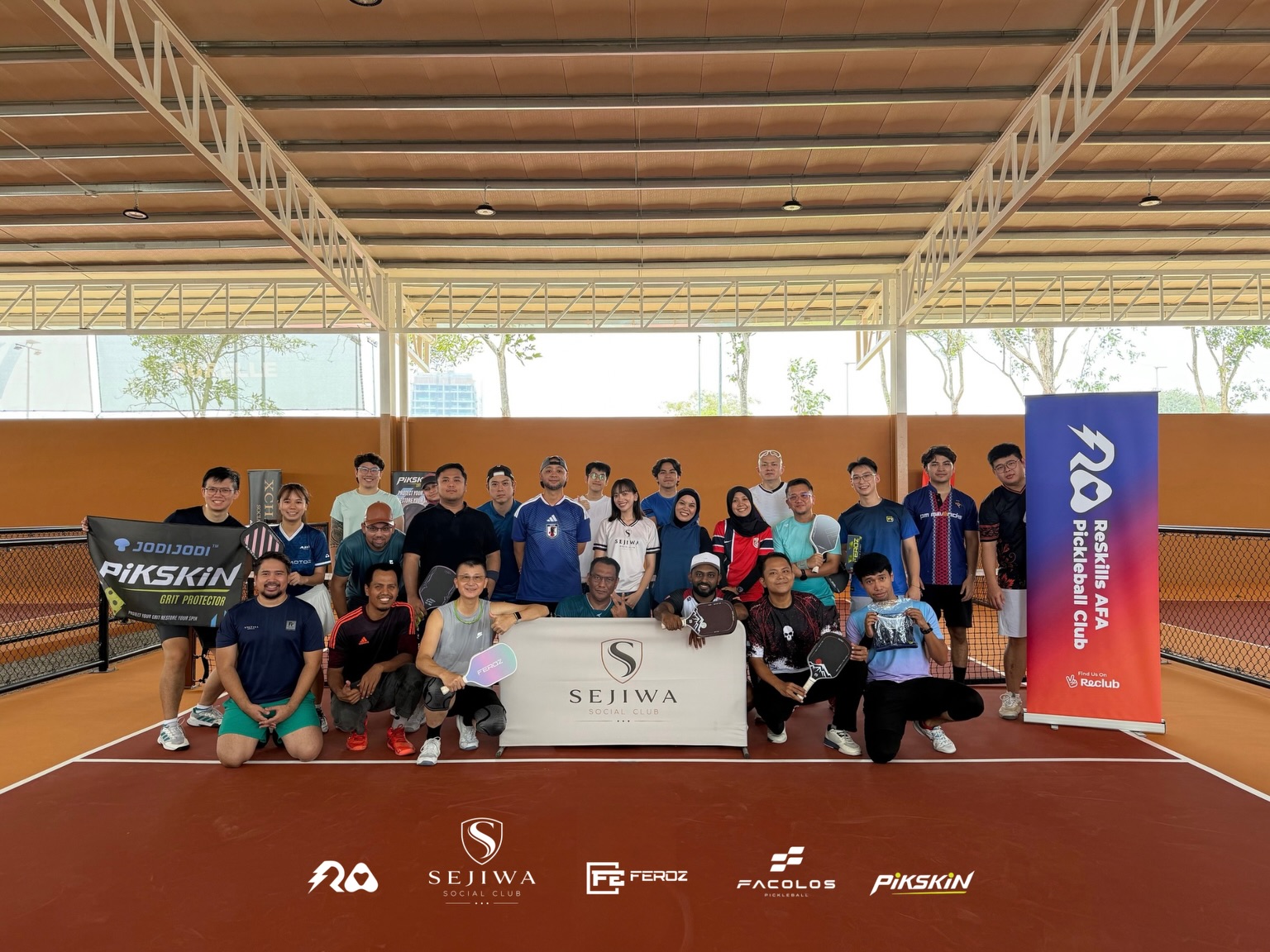 Players gathered around a Sejiwa Social Club net at the AFA community social with sponsor banners
