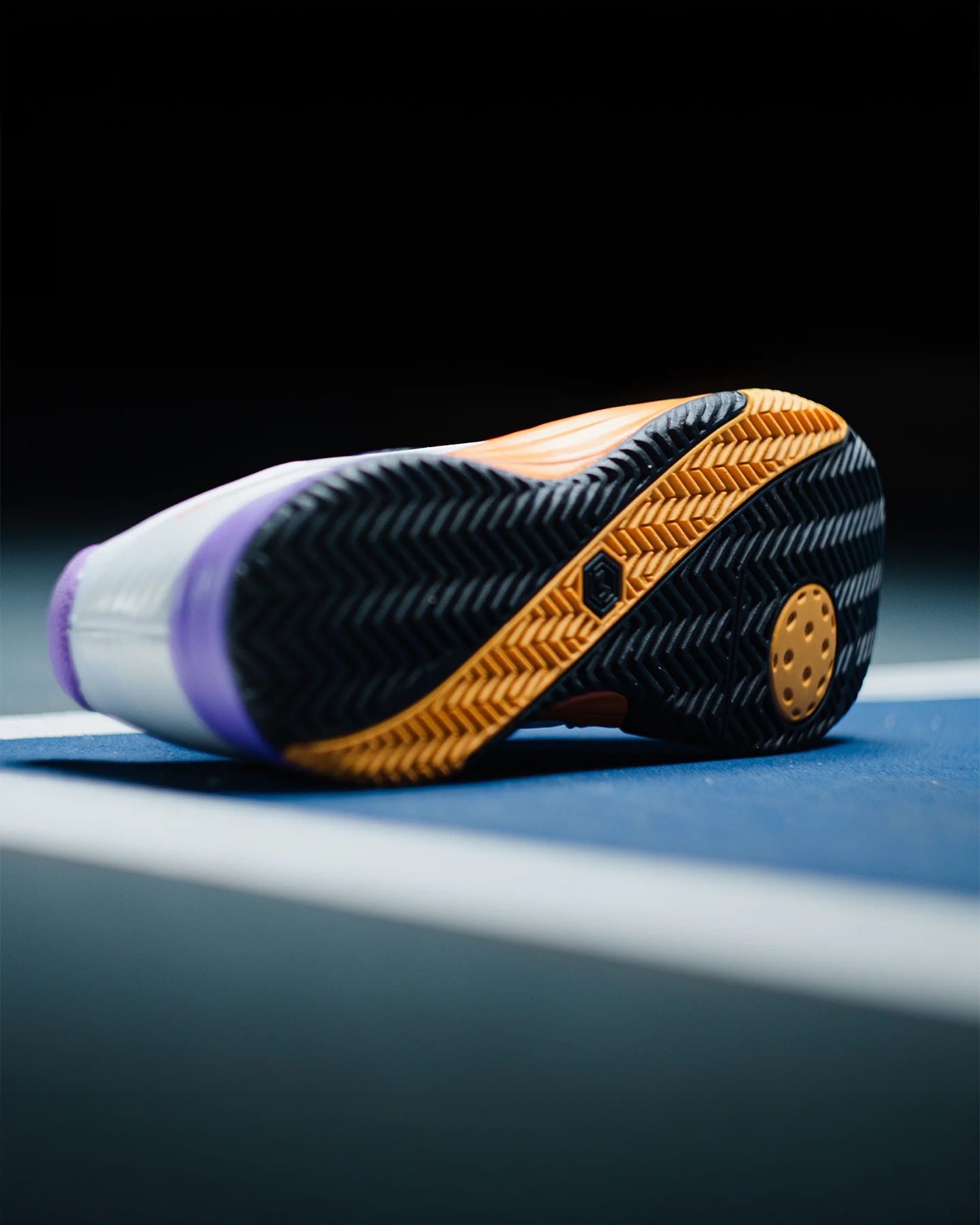 Close-up of the Friday x Montis Drop 1.0 outsole showing a black and gold herringbone tread with a pickleball-shaped pad