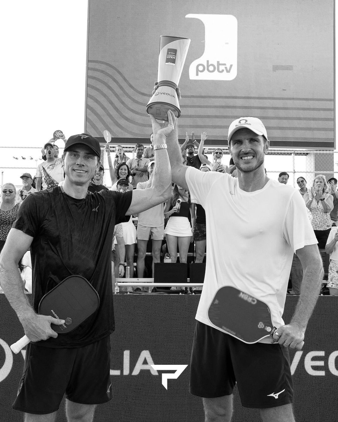 Two men in black and white holding the Veolia Arizona Open trophy aloft together, one with a Paddletek paddle and one with a CRBN paddle