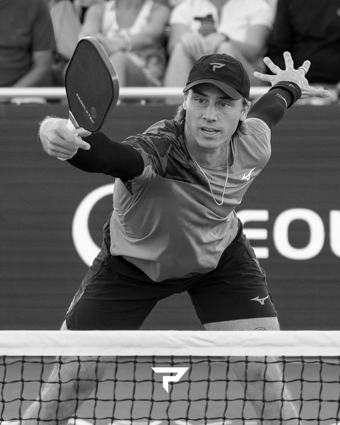 Christian Alshon stretching low at the net with a Paddletek paddle in a black and white photo from the Veolia Arizona Open