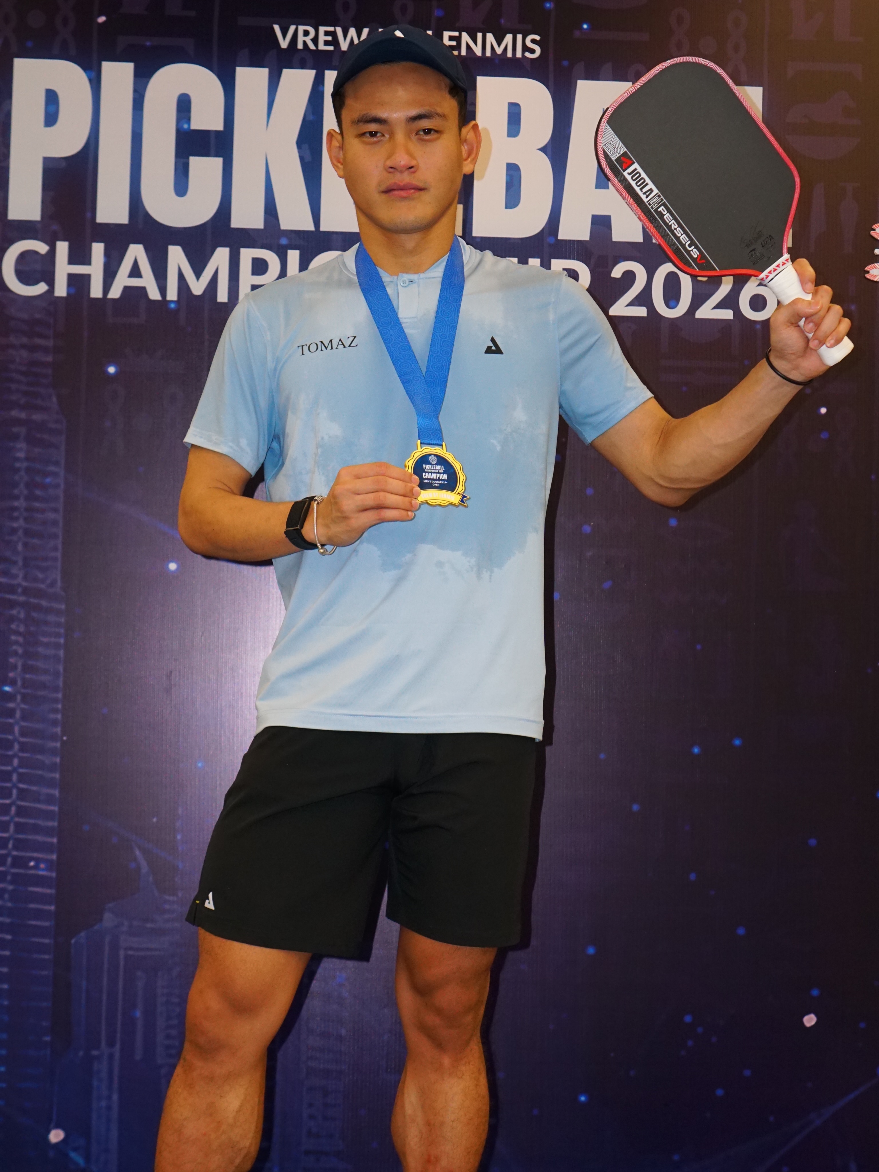 Aaiman Hamdan holding his gold medal and JOOLA Perseus paddle in front of the VREW by Lenmis Pickleball Championship 2026 backdrop