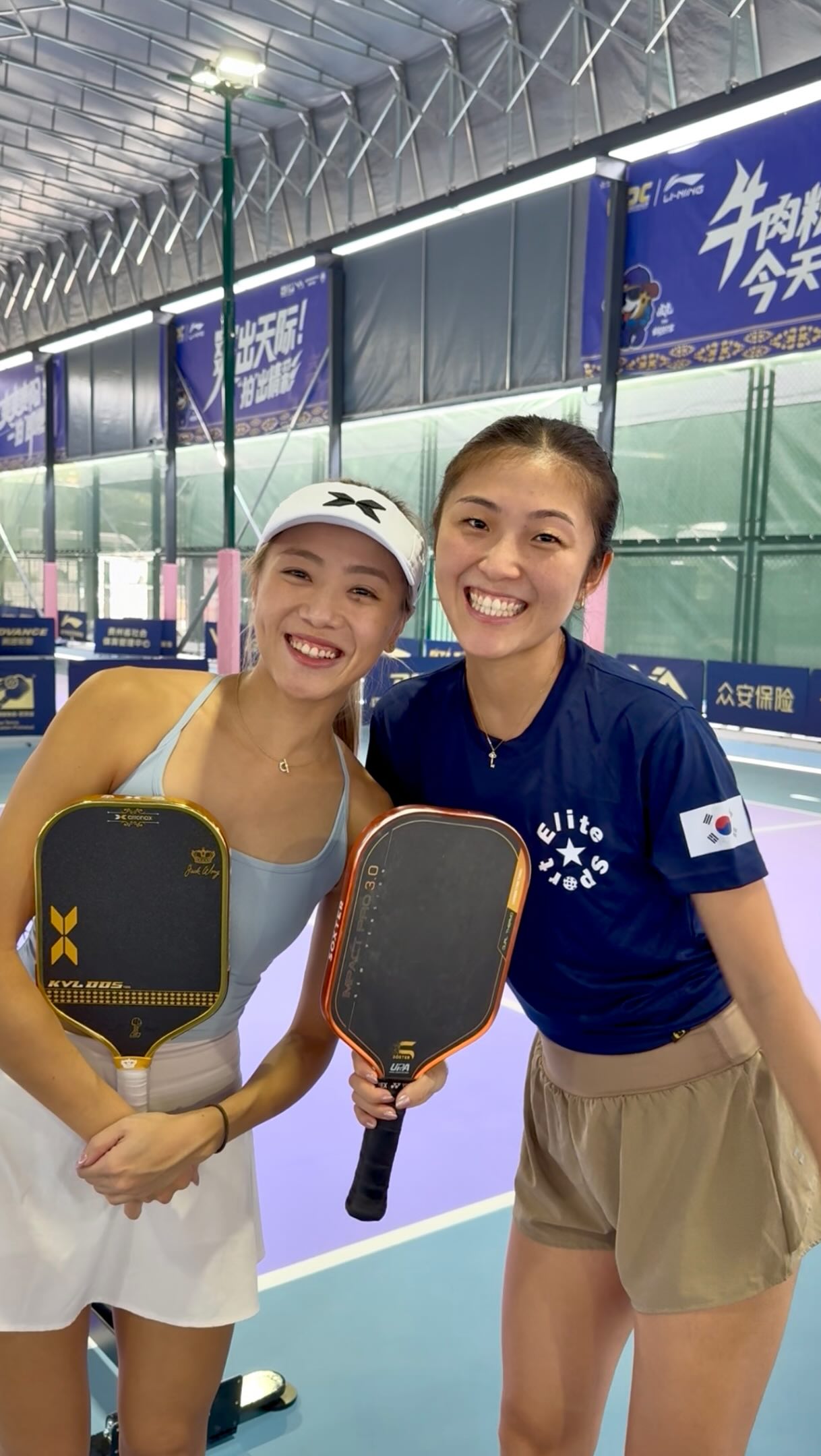 Agnes Fan and Connie Lee smiling together holding paddles in an indoor court during the CPC1000 Guiyang build-up