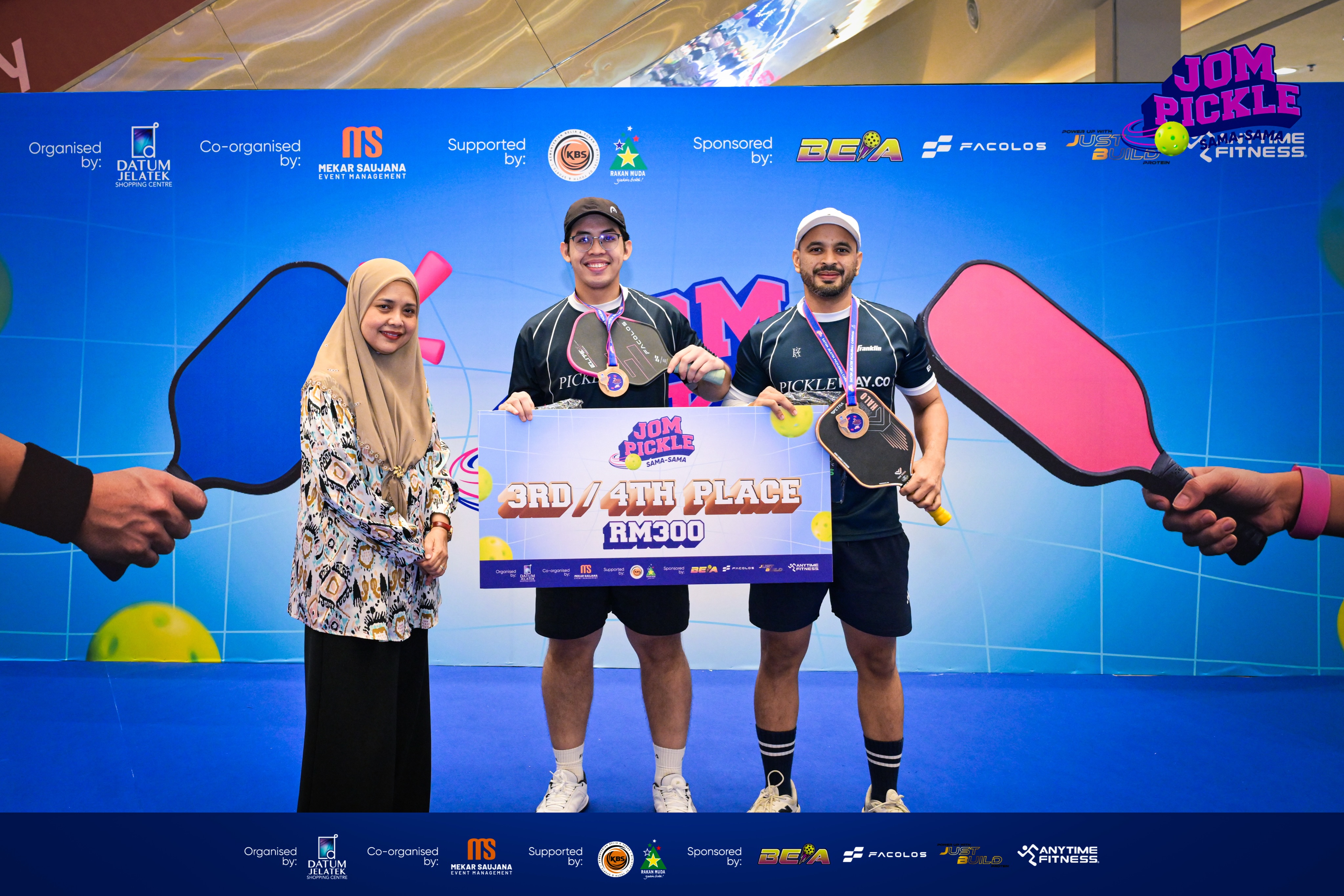 Two PicklePlayCo players with medals holding a 3rd/4th place RM300 board at Jom Pickle Sama-Sama