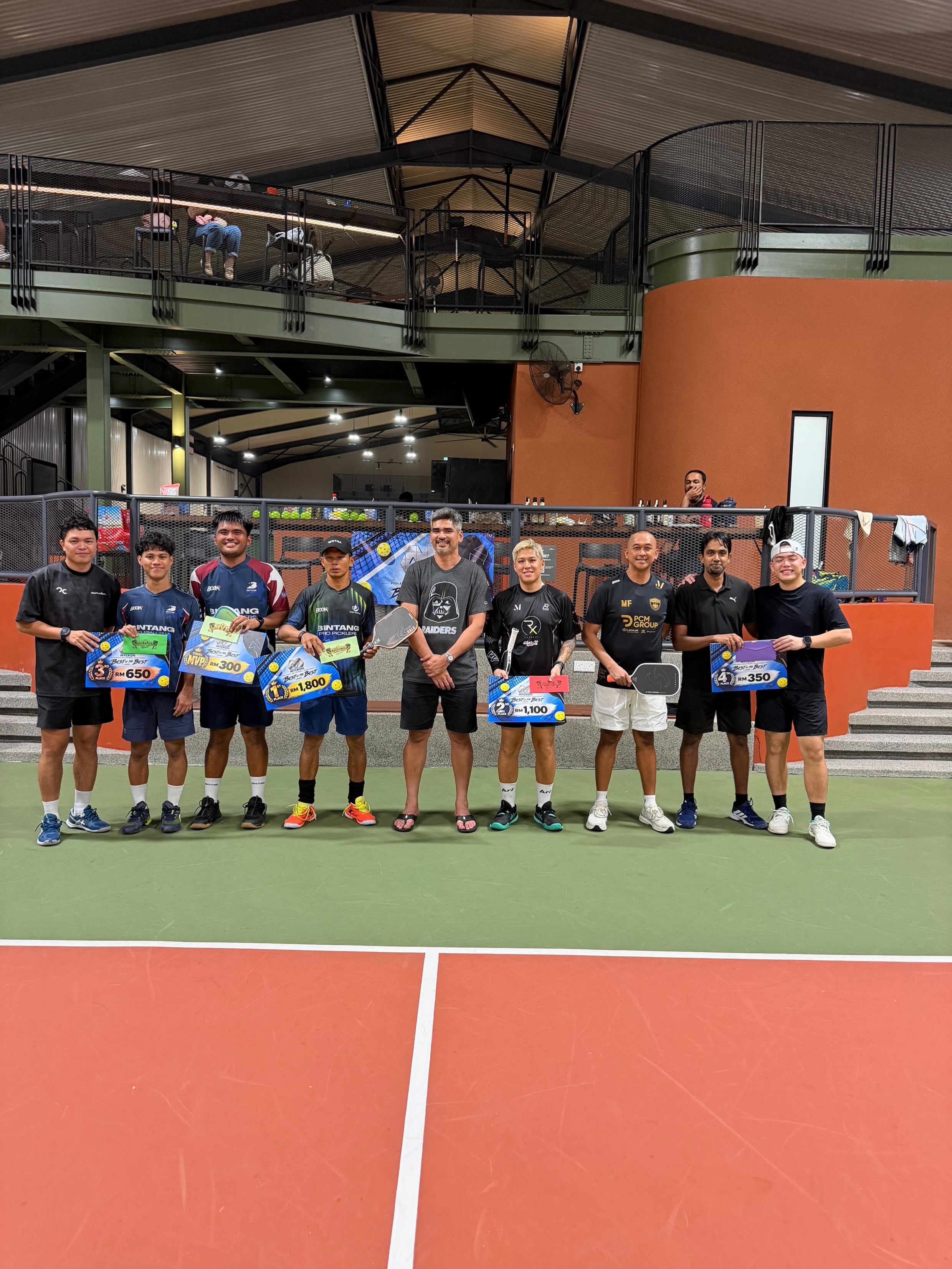 Nine people on court holding Mycron Invitational prize boards for 1st to 4th place and Final MVP