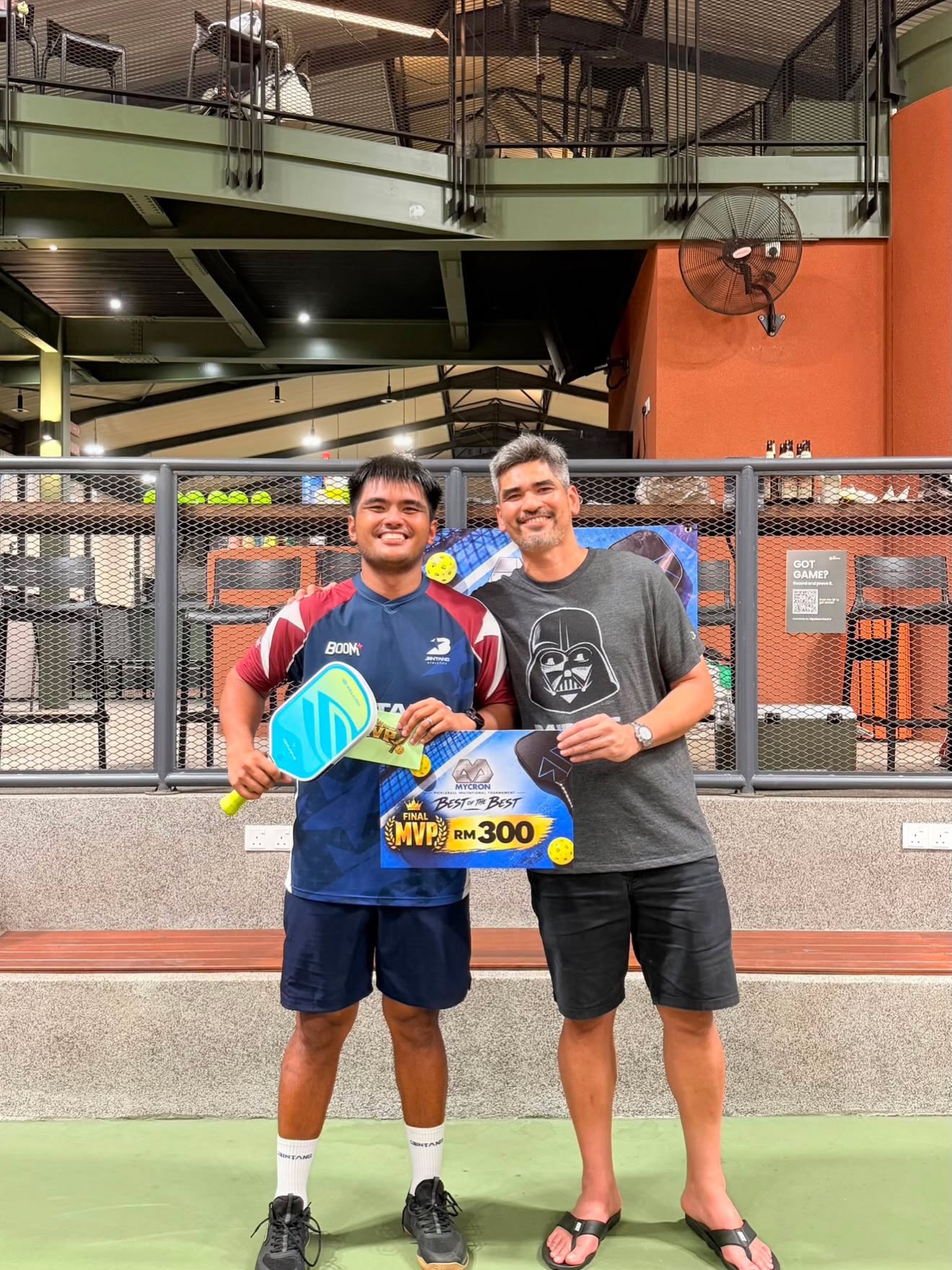 Assri holding the Mycron Invitational Final MVP RM300 board next to a man in a Raiders T-shirt