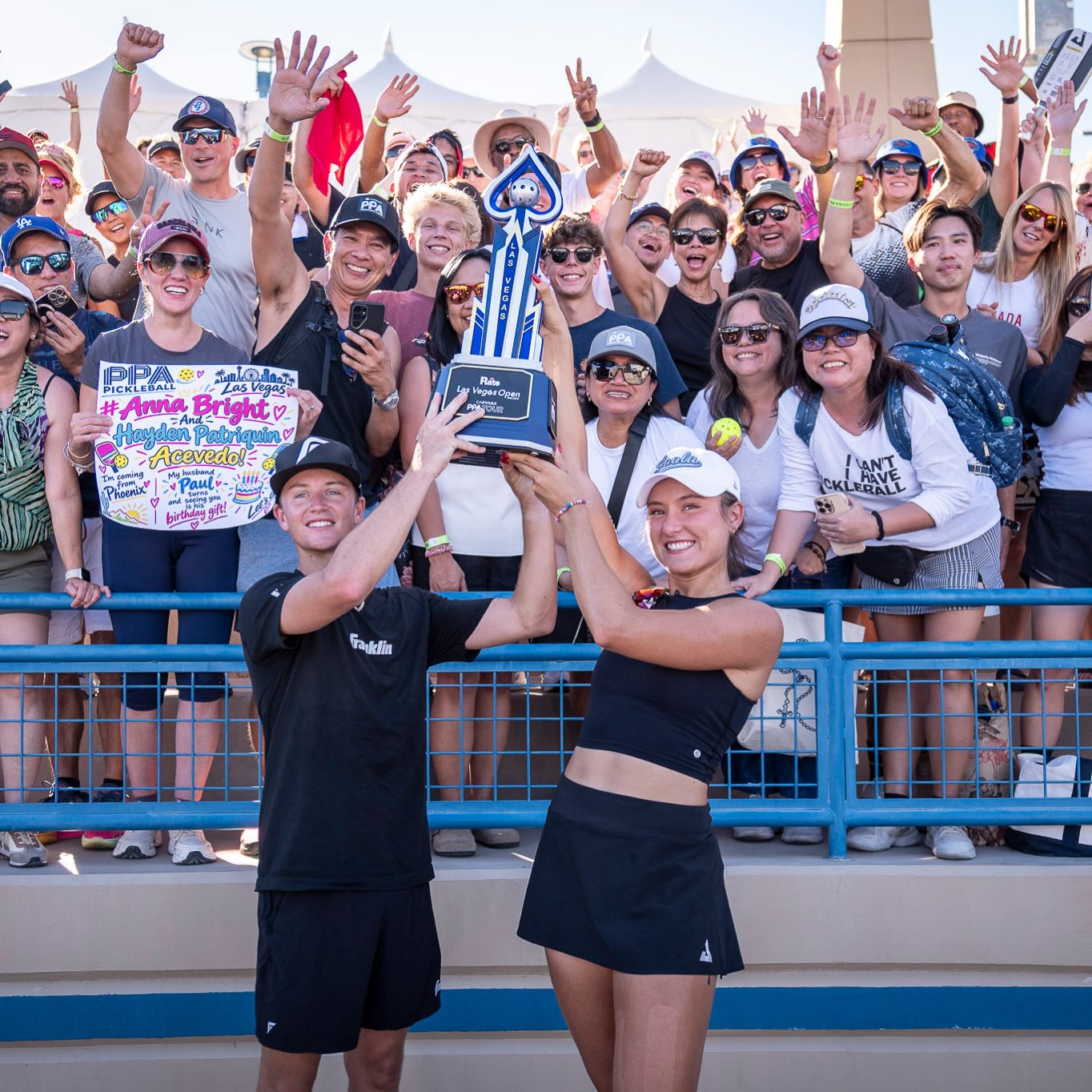 Anna Bright and Hayden Patriquin lifting a trophy in front of fans