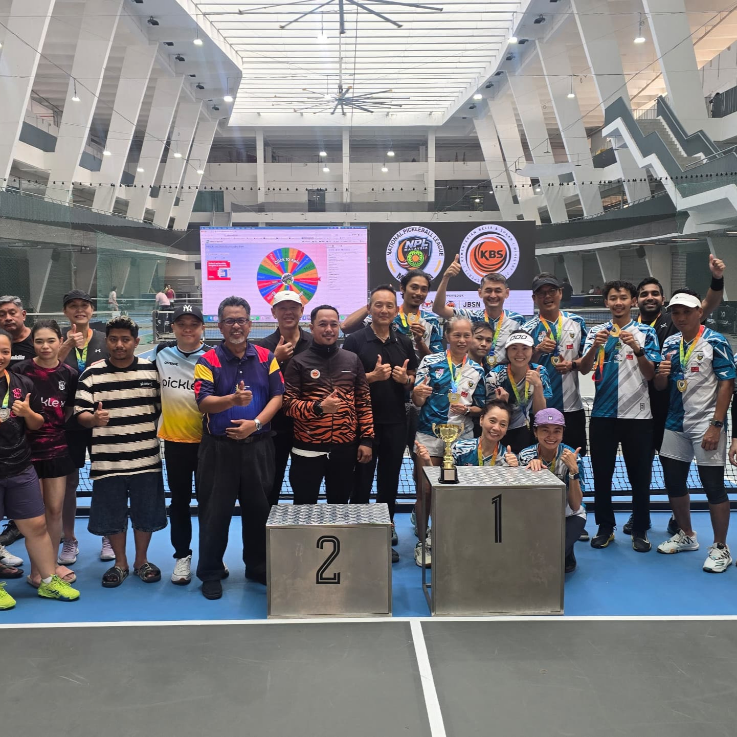 Players and guests pose with the trophy beneath the NPL Malaysia and KBS logos at Stadium KWC
