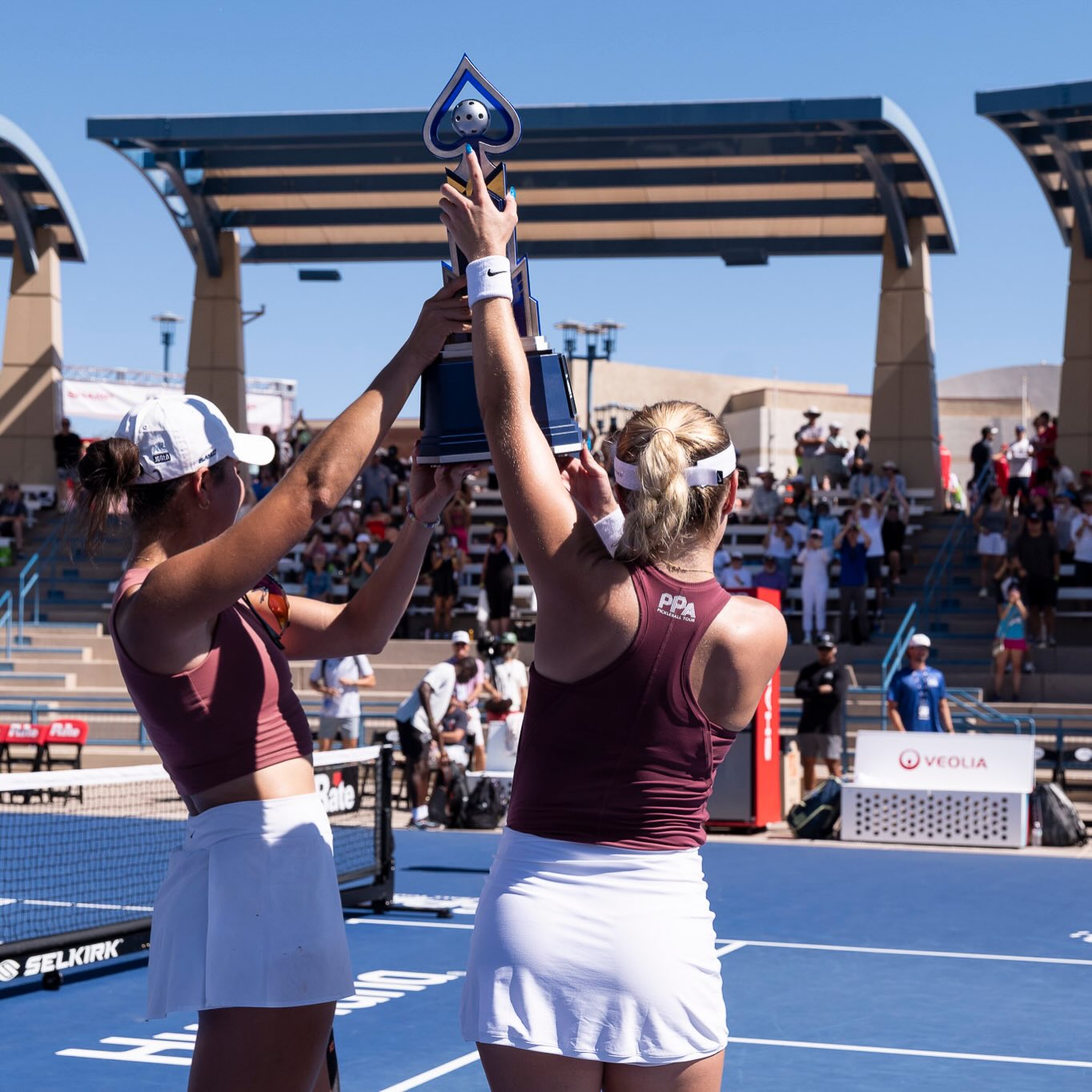 Two players lifting the Las Vegas Open women's doubles trophy