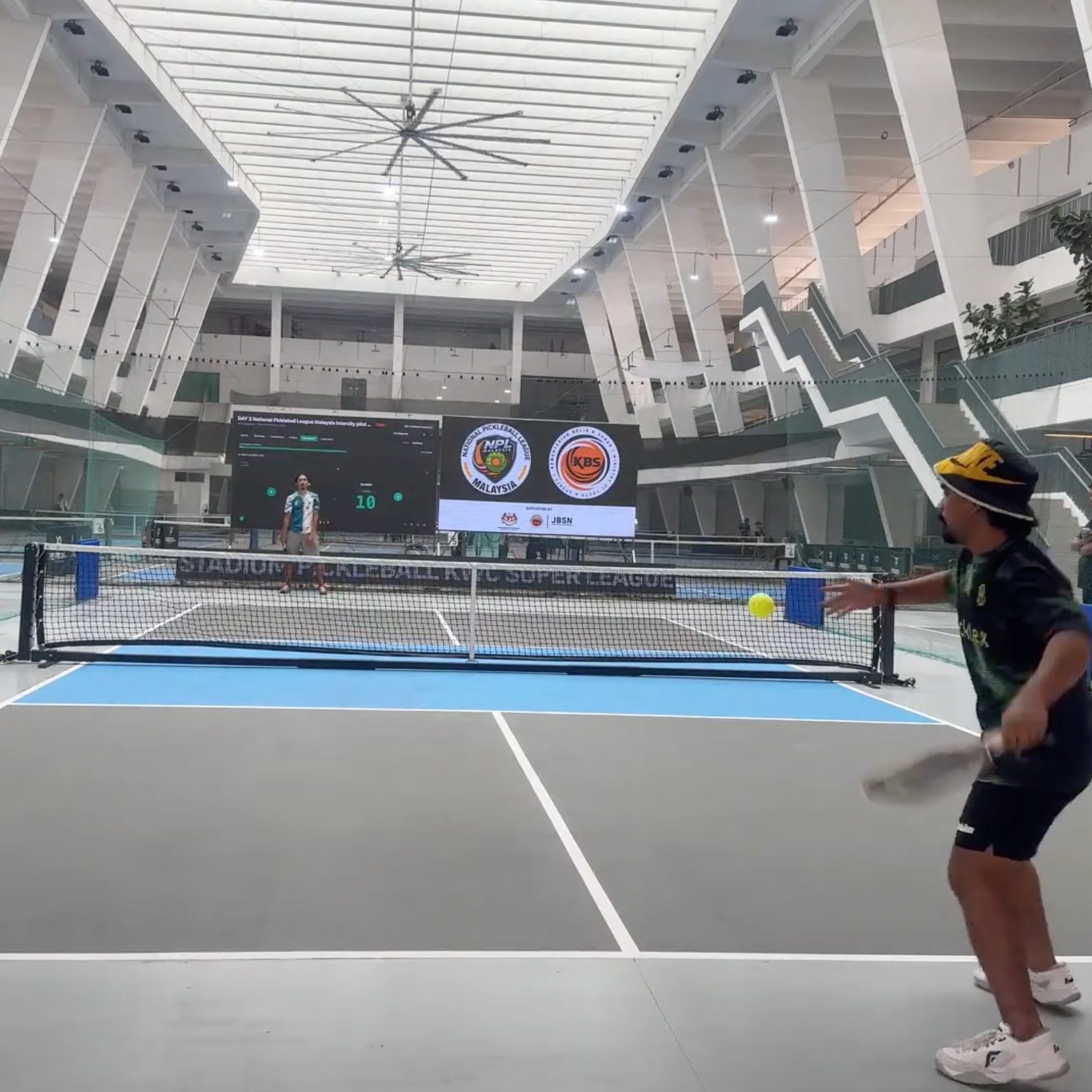 Match action on court at Stadium KWC with the NPL Malaysia and KBS logos on the big screen