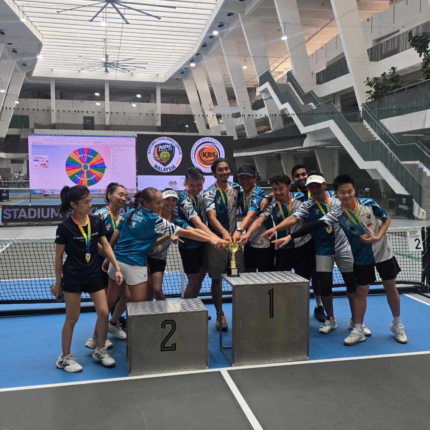 Players gather around the trophy on the podium at Stadium KWC