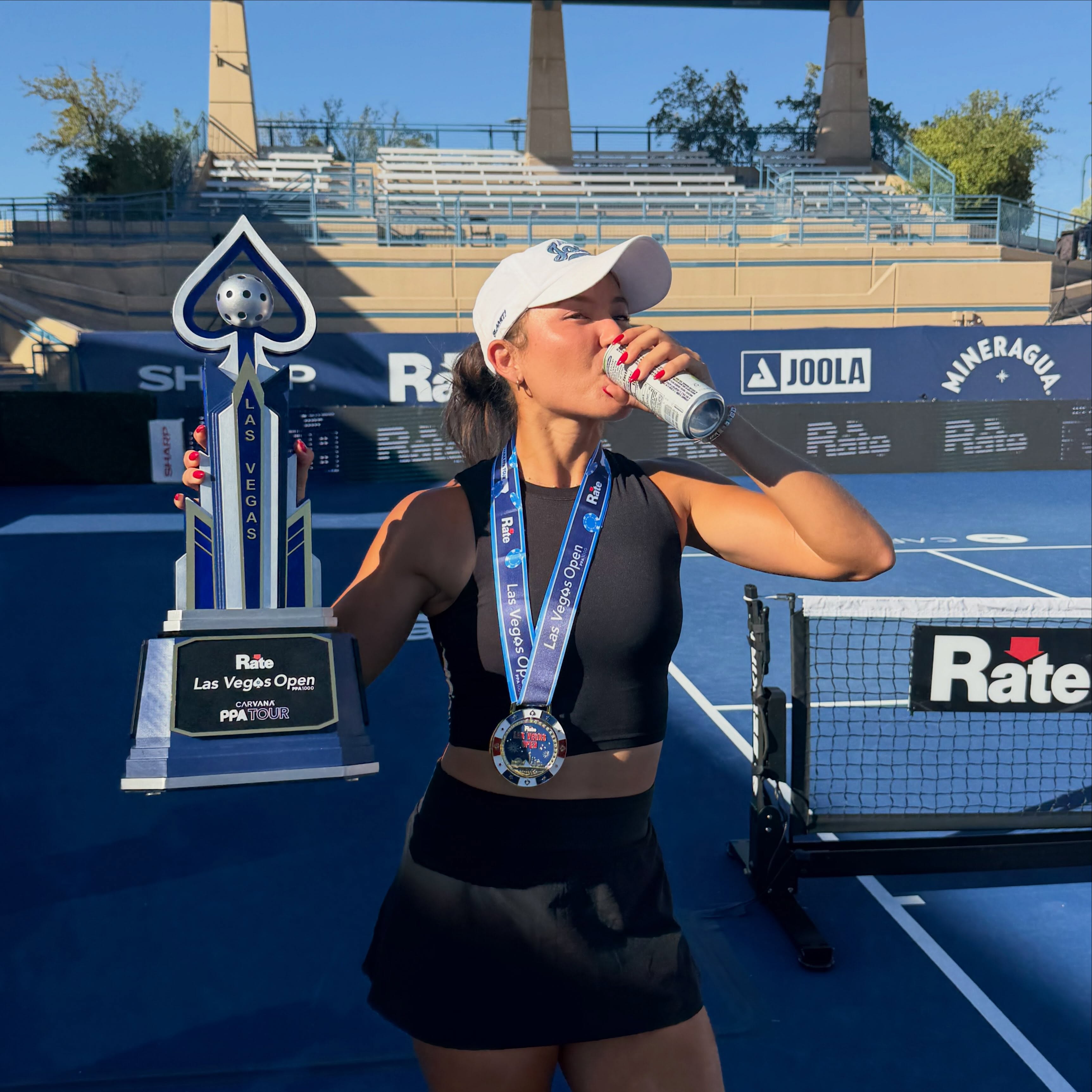 Anna Bright holding the Las Vegas Open trophy and medal at the net