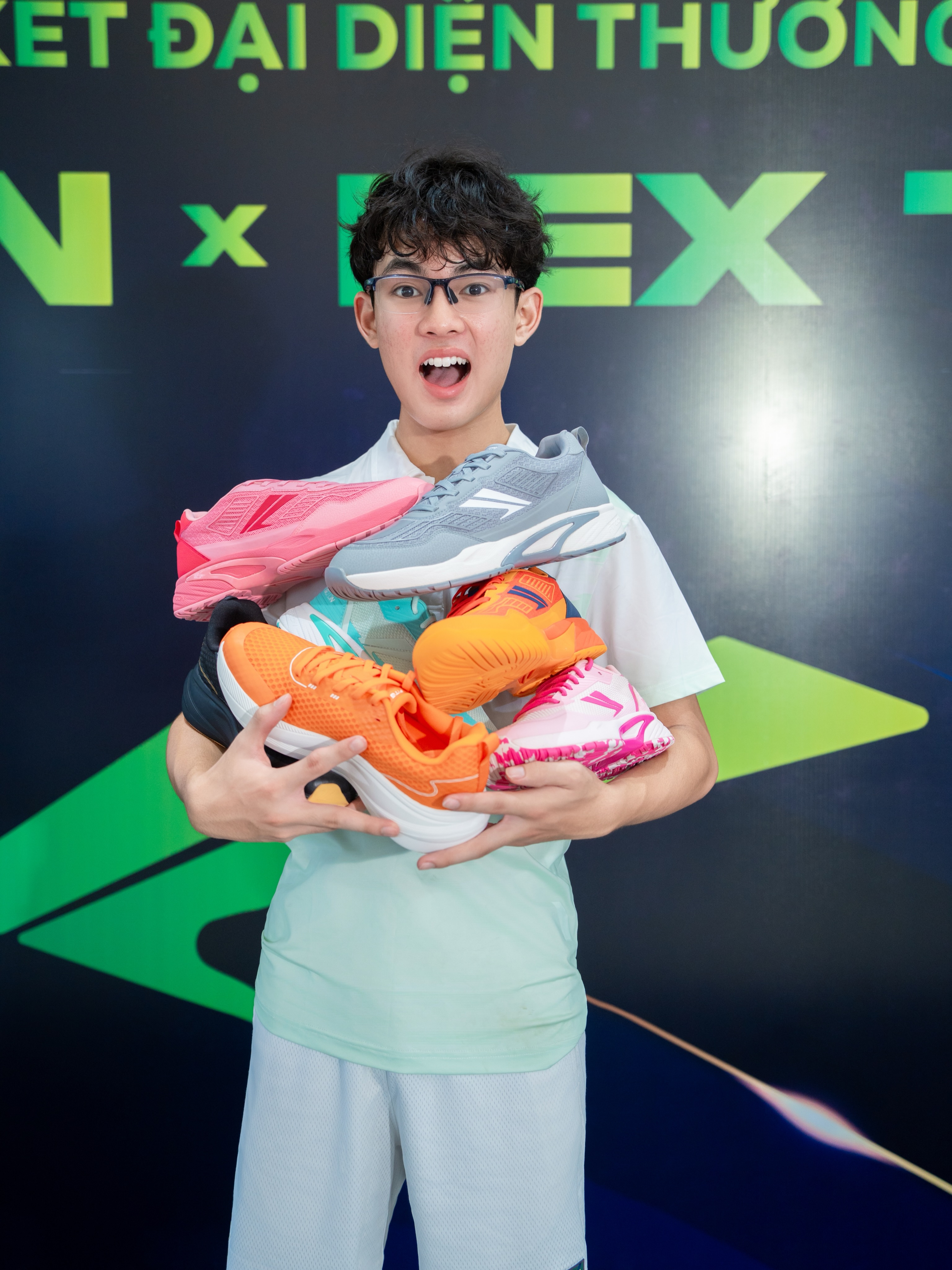 Rex Thais with his arms full of Fitgon shoes in pink, grey, orange and white