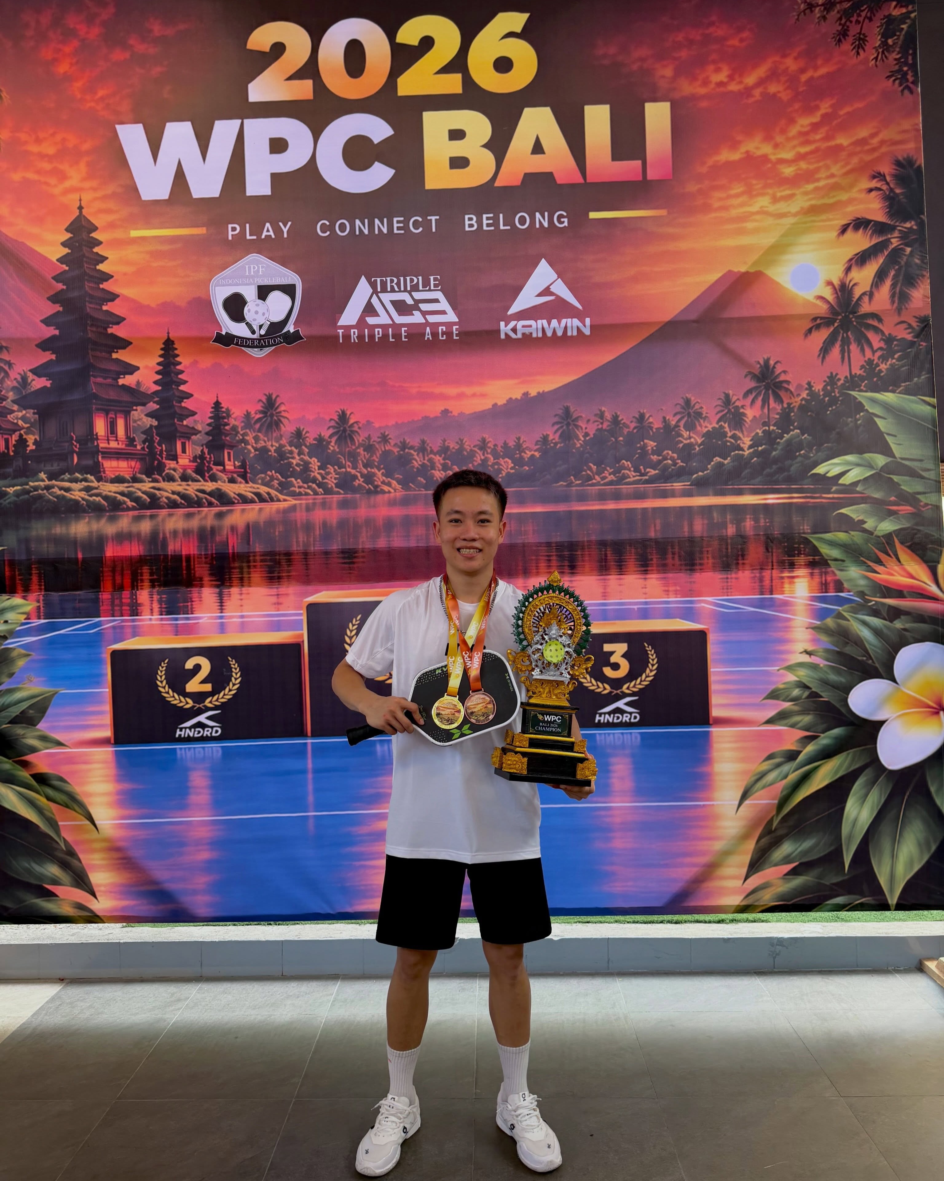 Lagger Chan in front of the WPC Bali backdrop with medals and the trophy