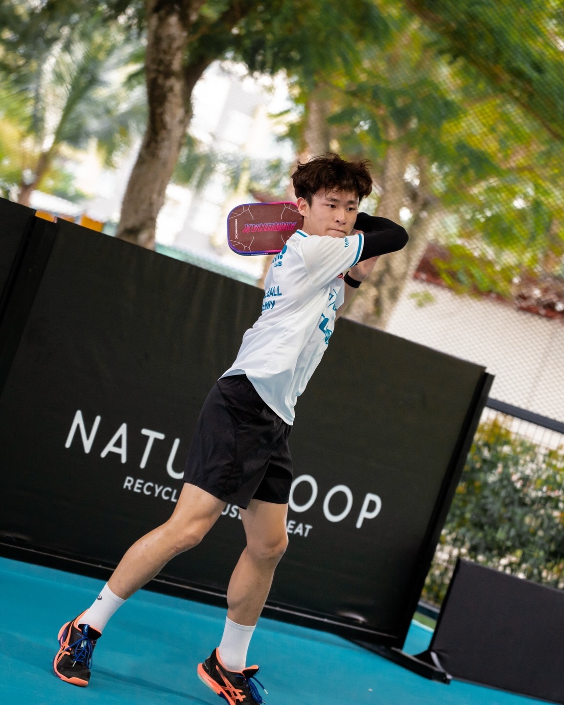 Yihern playing a backhand with an Arronax paddle