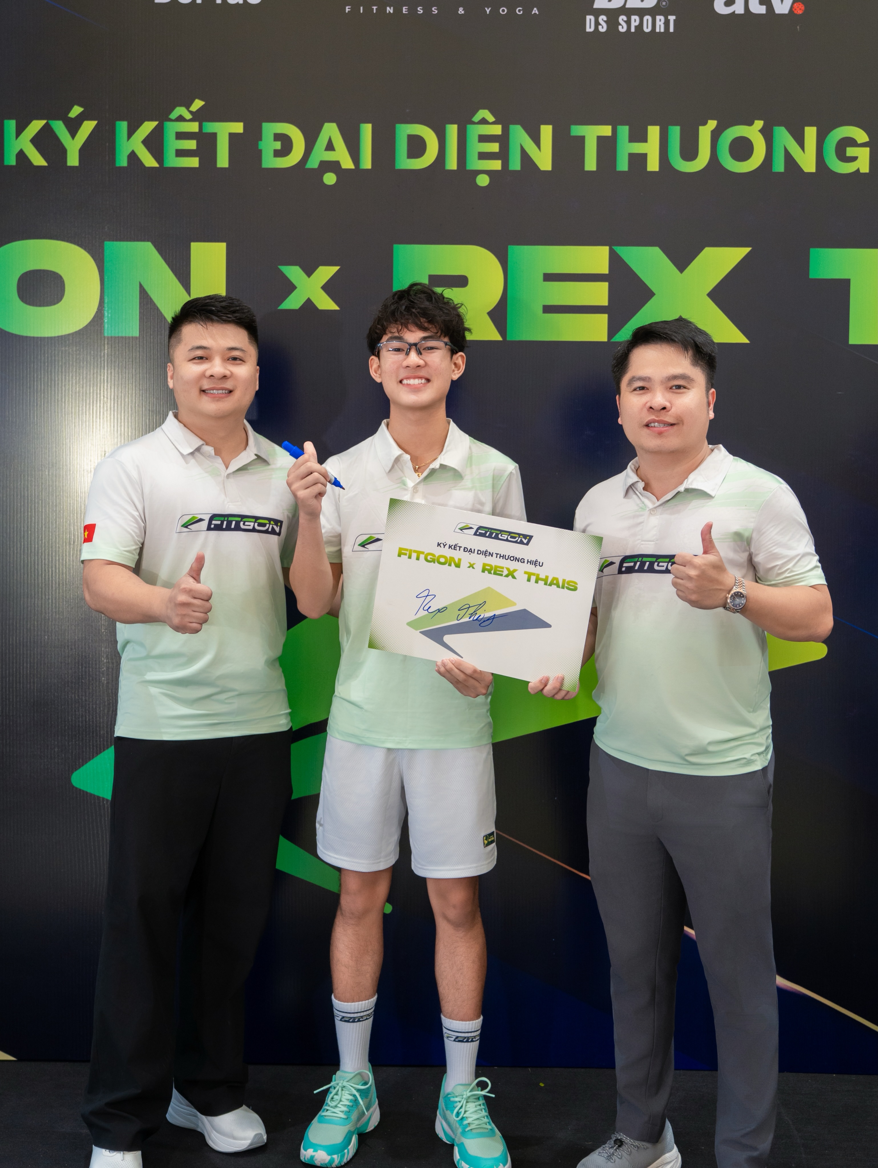 Rex Thais holding a signed Fitgon x Rex Thais board between two men in Fitgon polos