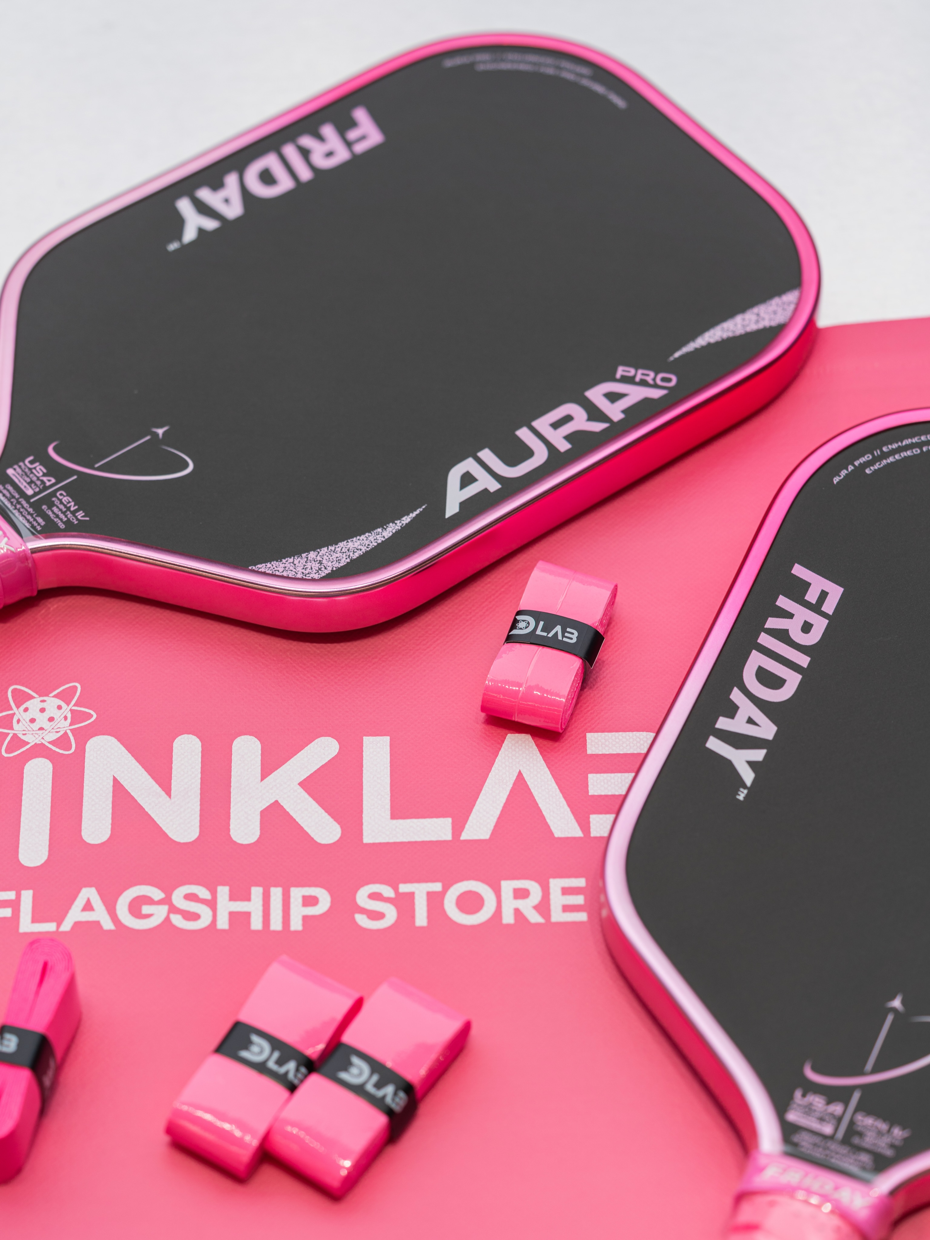 Two Friday Aura Pro paddles on a pink mat reading Dinklab Flagship Store.