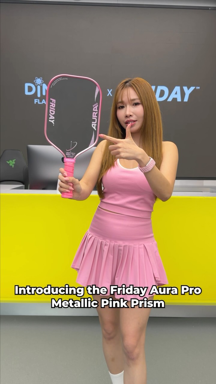 A woman in a pink outfit holds the paddle in front of a Dinklab and Friday backdrop.