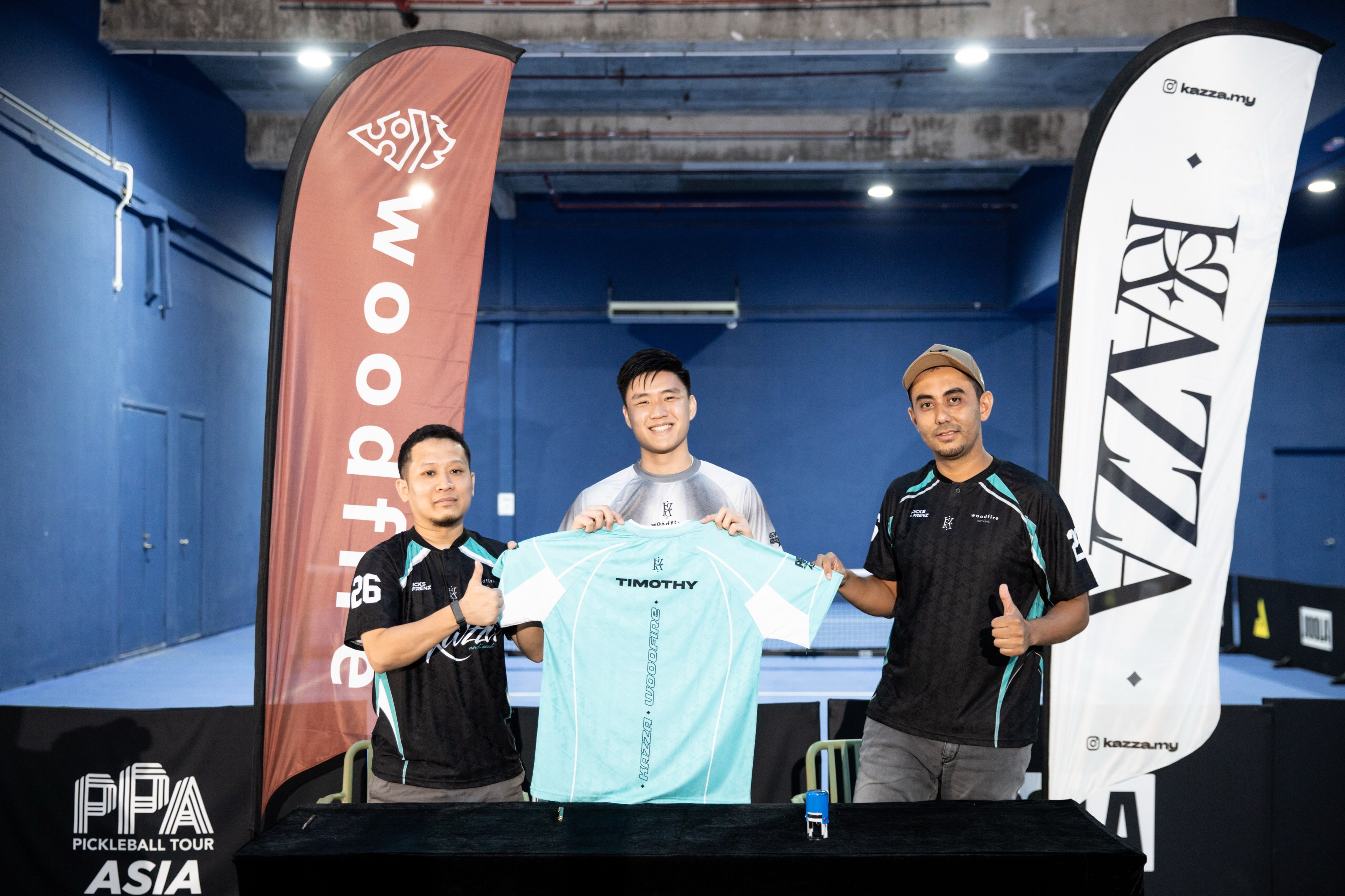 A light blue jersey with the name Timothy held up between two men in matching black jerseys
