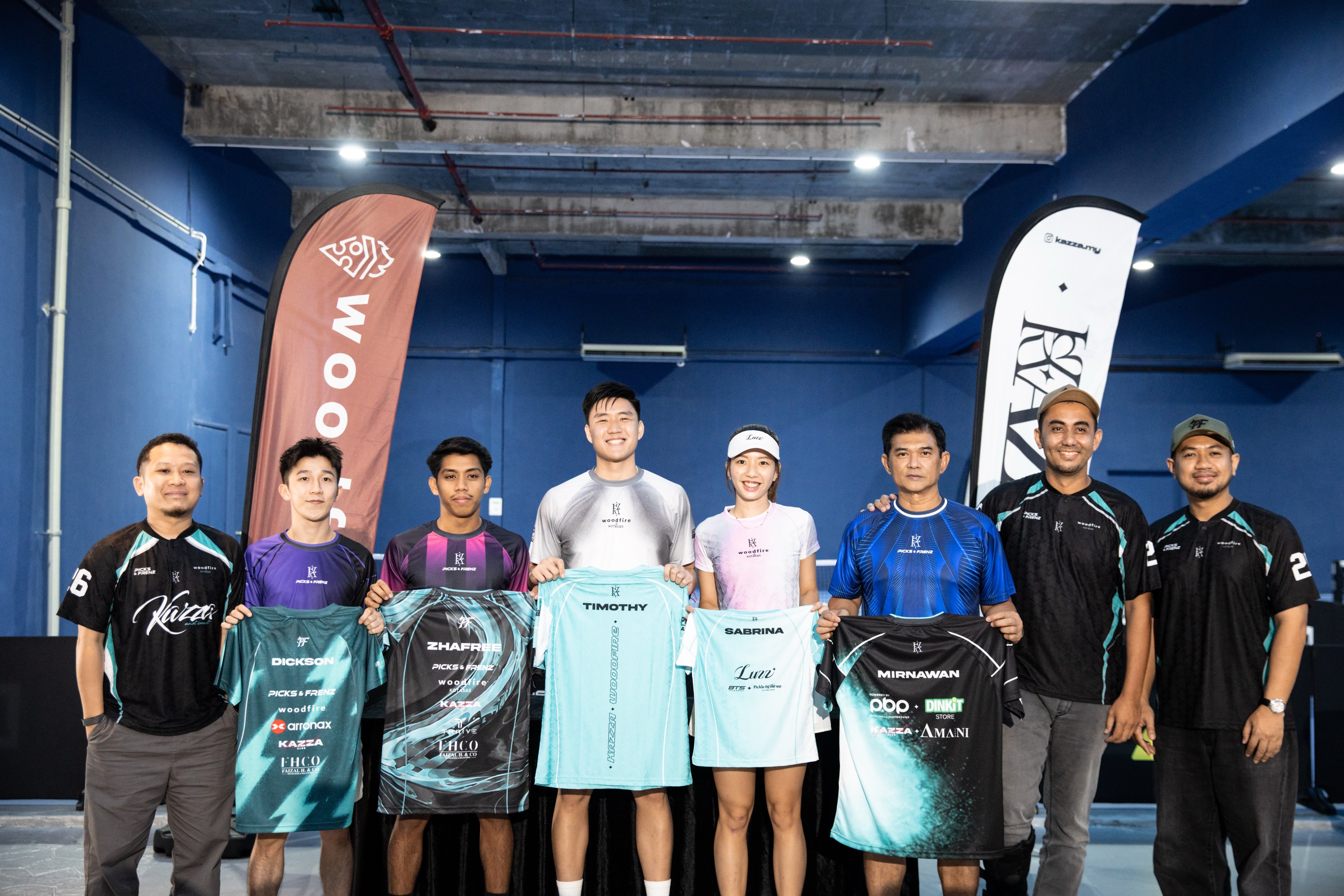 Five players holding named jerseys with three people in Kazza and Woodfire shirts
