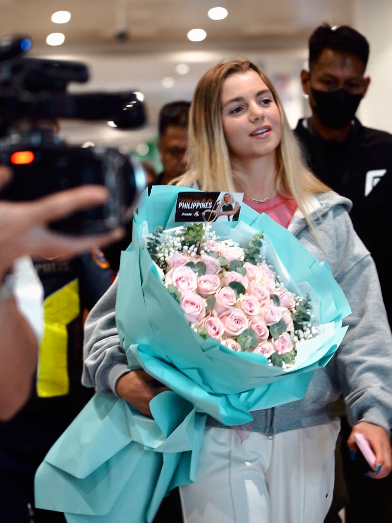 Anna Leigh Waters carrying a bouquet in the arrivals area