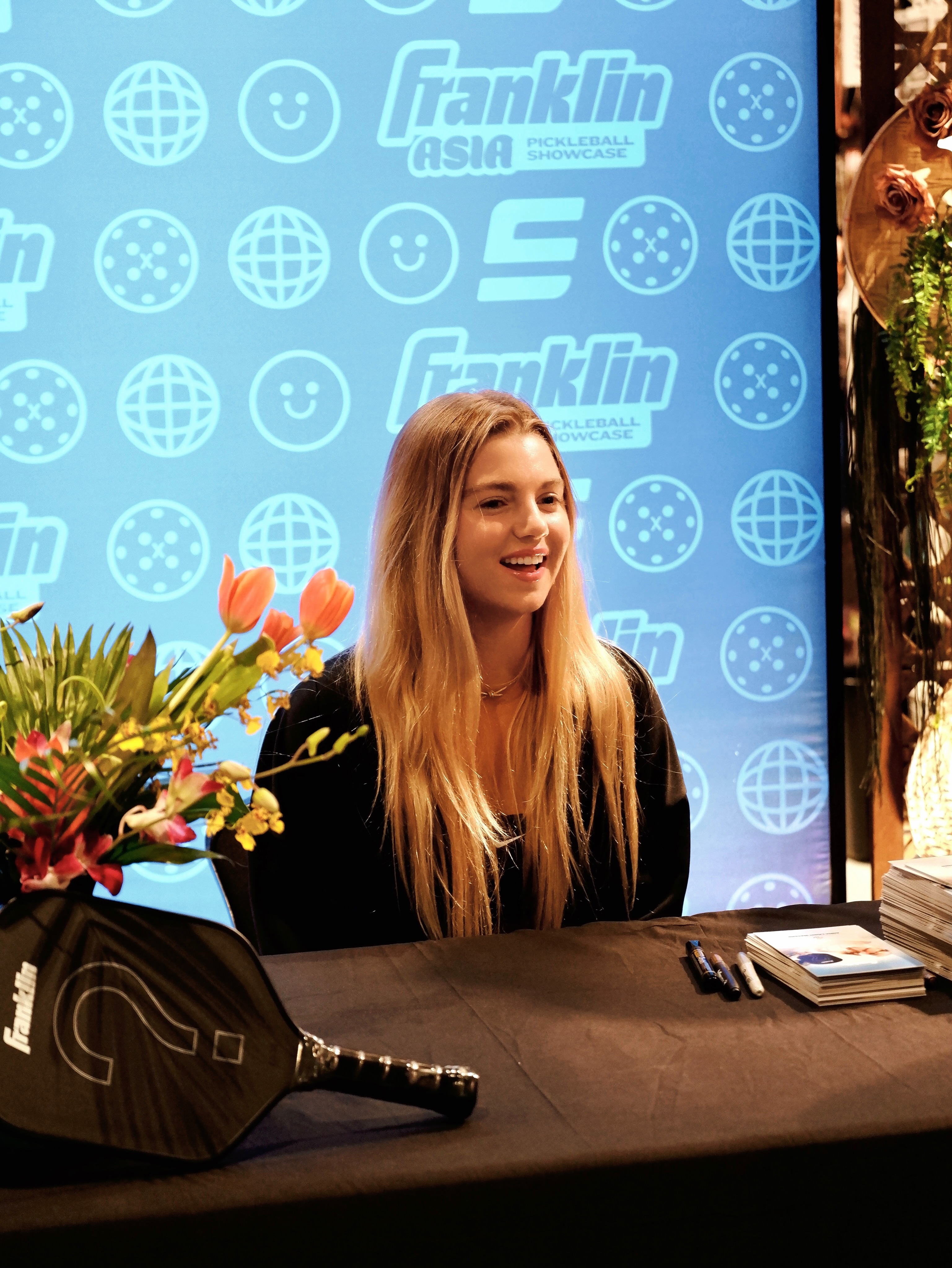 Anna Leigh Waters seated in front of the Franklin Asia Pickleball Showcase backdrop at Chris Sports
