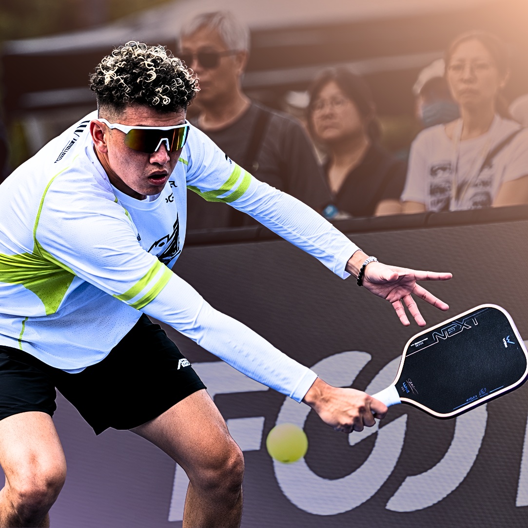 Ricky Lin lunging for a ball in a white and lime AEPL shirt, holding a Wika Next-X paddle